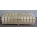 A large upholstered ottoman, with striped material and brass loop handle