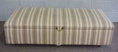 A large upholstered ottoman, with striped material and brass loop handle