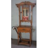 An Edwardian oak hall stand, circa 1910, with a shaped mirror set back with seven hat hooks, over