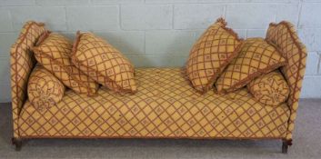 A French style day bed, with arched ends, currently upholstered in gold with a red trellis stripe,