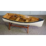 A wooden scale model of a clinker built rowing boat, with painted sides and a pair of oars, 120cm