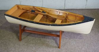 A wooden scale model of a clinker built rowing boat, with painted sides and a pair of oars, 120cm