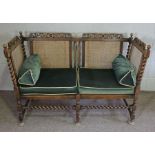 An oak framed Jacobean style settee, circa 1900, with carved crest rail, twist column supports,
