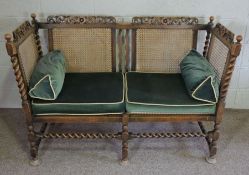 An oak framed Jacobean style settee, circa 1900, with carved crest rail, twist column supports,