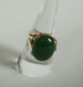 An 18 carat gold and green jade ring, ring size P, the oval cabochon stone with dark spinach green