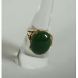 An 18 carat gold and green jade ring, ring size P, the oval cabochon stone with dark spinach green