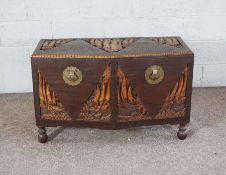 An early 20th century Chinese camphor chest, with carved panels depicting sailing vessels, set on