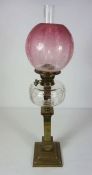 A Victorian brass column oil lamp, circa 1870, with a cranberry glass shade, clear reservoir and the