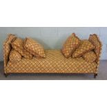 A French style day bed, with arched ends, currently upholstered in gold with a red trellis stripe,