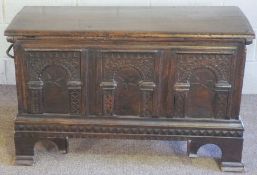 An oak coffer, 16th century and later, with a lightly curved hinged lid, over a triple arch