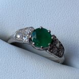 An emerald and diamond engagement ring, 18 carat white gold setting, with central round cut emerald,