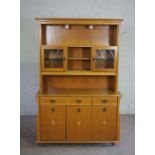 A modern light oak veneered china cabinet, with glass fronted cabinets and niches over a base with