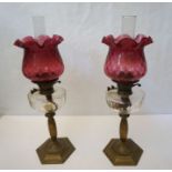 A pair of Victorian brass and cranberry glass oil lamps, late 19th century, with clear reservoirs