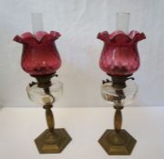 A pair of Victorian brass and cranberry glass oil lamps, late 19th century, with clear reservoirs