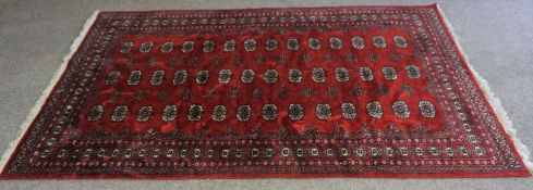 A Buchara carpet, Pakistan, late 20th century, with multiple guls in three lines on a red field,