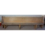 A large church pew, with panelled table and trestle supports, 92cm high, 305cm long