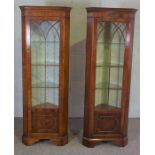 A pair of George III style mahogany veneered corner display cabinets, each with a glazed door and