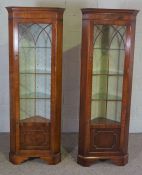 A pair of George III style mahogany veneered corner display cabinets, each with a glazed door and