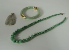 A pale green jadeite and 14 carat gold hinged bangle, 7cm diameter; together with a mutton fat