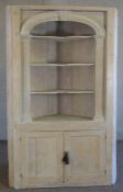 A George III style limed pine corner cabinet, modern, with an arched bookshelf niche with three