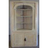 A George III style limed pine corner cabinet, modern, with an arched bookshelf niche with three