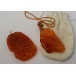 Two orange jade carved pendants, one with blossom & fruit, the other similar, 5.5cm long (2)