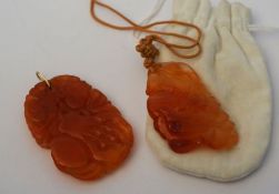 Two orange jade carved pendants, one with blossom & fruit, the other similar, 5.5cm long (2)