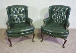 A pair of George III style green leather wing armchairs, 20th century, of compact form, with
