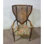 An early 20th century wing backed caned armchair, 110cm high