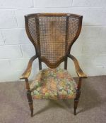 An early 20th century wing backed caned armchair, 110cm high