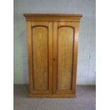 A Victorian ash double wardrobe, circa 1900, with two moulded panelled doors, the interior with