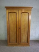 A Victorian ash double wardrobe, circa 1900, with two moulded panelled doors, the interior with
