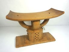 An African carved hardwood stool, circa 1987, with a gently curved seat and faceted and pierced