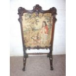 A Victorian mahogany framed firescreen, with an central embroidered panel within carved supports and