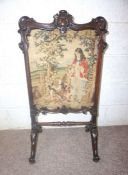 A Victorian mahogany framed firescreen, with an central embroidered panel within carved supports and