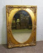 A vintage George III style wall mirror, with oval bevelled plate in a rectangular composition gilt