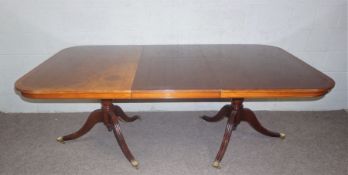 A large George III style mahogany veneered twin pillar dining table, with a single additional