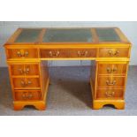 A yew veneered George III style reproduction kneehole desk, with a leathered top and arrangement