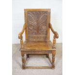 An oak wainscott armchair, 17th century style, with a carved back decorated with a stylised