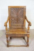 An oak wainscott armchair, 17th century style, with a carved back decorated with a stylised
