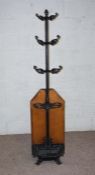 A Victorian wrought iron and oak hall stand, with six hat hooks, five umbrella holders and a drip