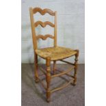 A set of four ash framed ladder back dining chairs, 19th century, with rush seats, each with an