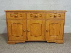 A modern oak dresser base, with three drawers and three cabinet doors. 77cm high, 130cm wide