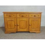 A modern oak dresser base, with three drawers and three cabinet doors. 77cm high, 130cm wide