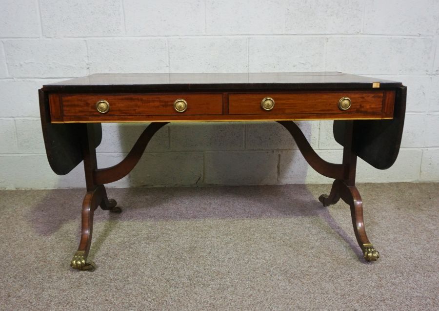 A Regency mahogany sofa table, circa 1810, with a drop leaf cross-banded top, over two drawers and