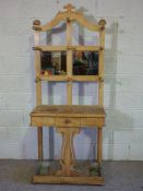 A late Victorian oak hall stand, circa 1900, with an arched top, with nine hat hooks over a small