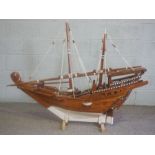 A large model of an Arabian Dhow, painted and rigged, of planked construction, set on a stand, 110cm