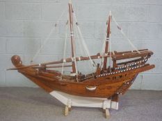 A large model of an Arabian Dhow, painted and rigged, of planked construction, set on a stand, 110cm