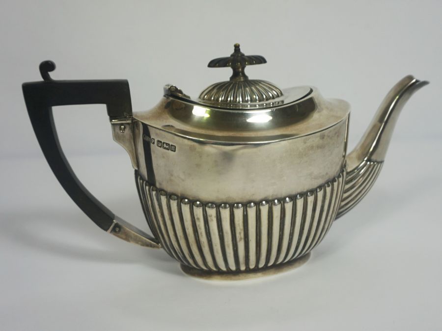 An Edwardian silver teapot, hallmarked Sheffield 1905, of oval part fluted form, with ebonized