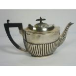 An Edwardian silver teapot, hallmarked Sheffield 1905, of oval part fluted form, with ebonized